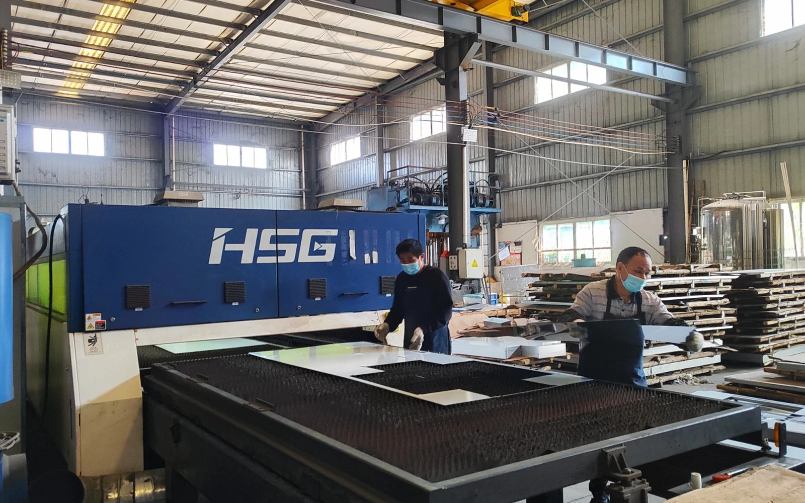 Operators preparing stainless steel sheets at a laser-cutting machine